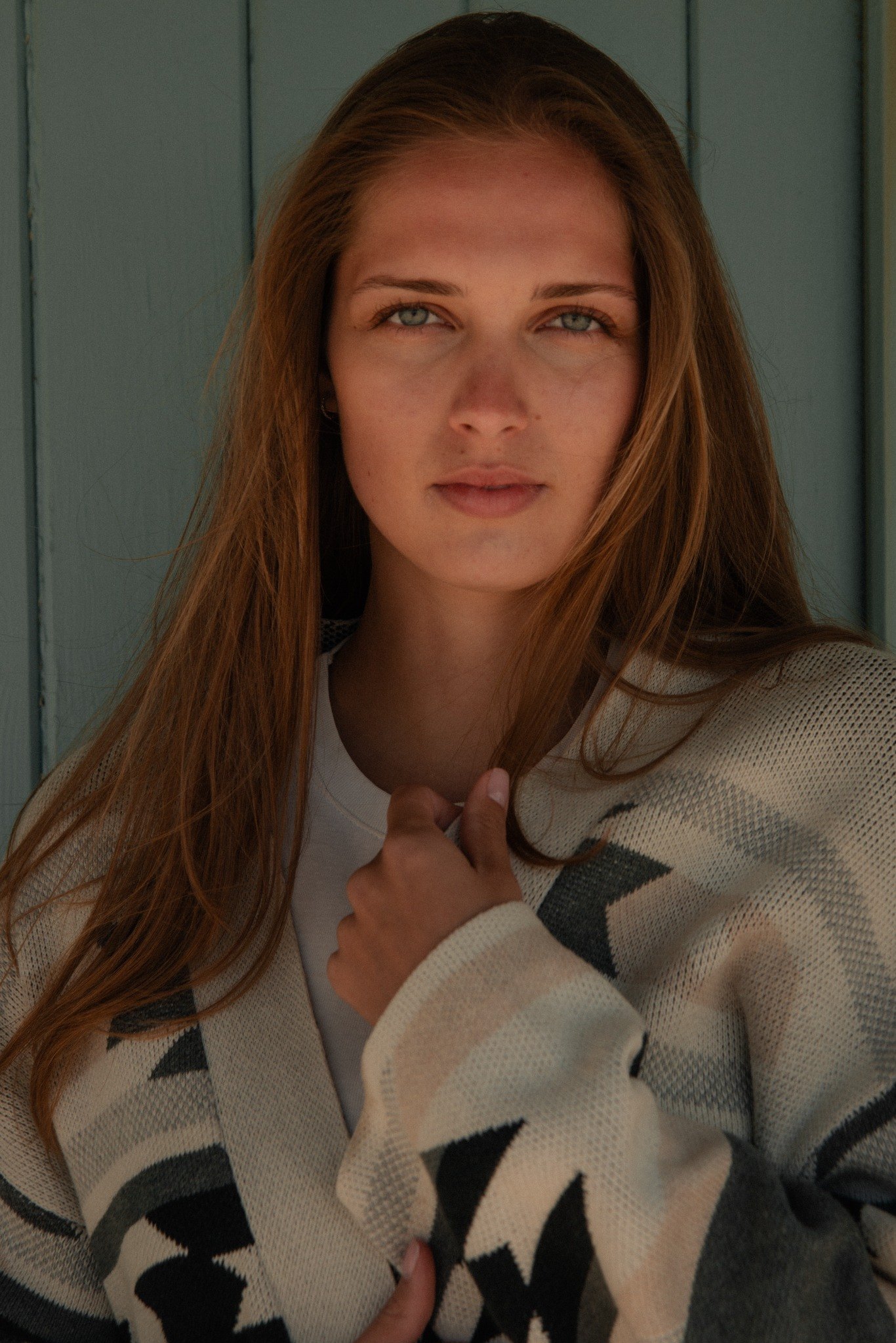 Fashion portrait in patterned cardigan at a pale blue beach hut by Lucy Rappolt