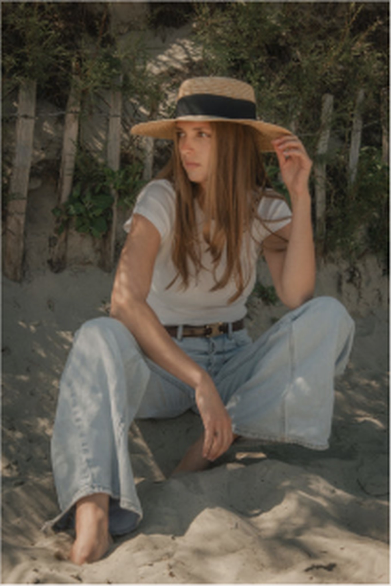 Seated beach fashion portrait in straw hat and denim by Lucy Rappolt